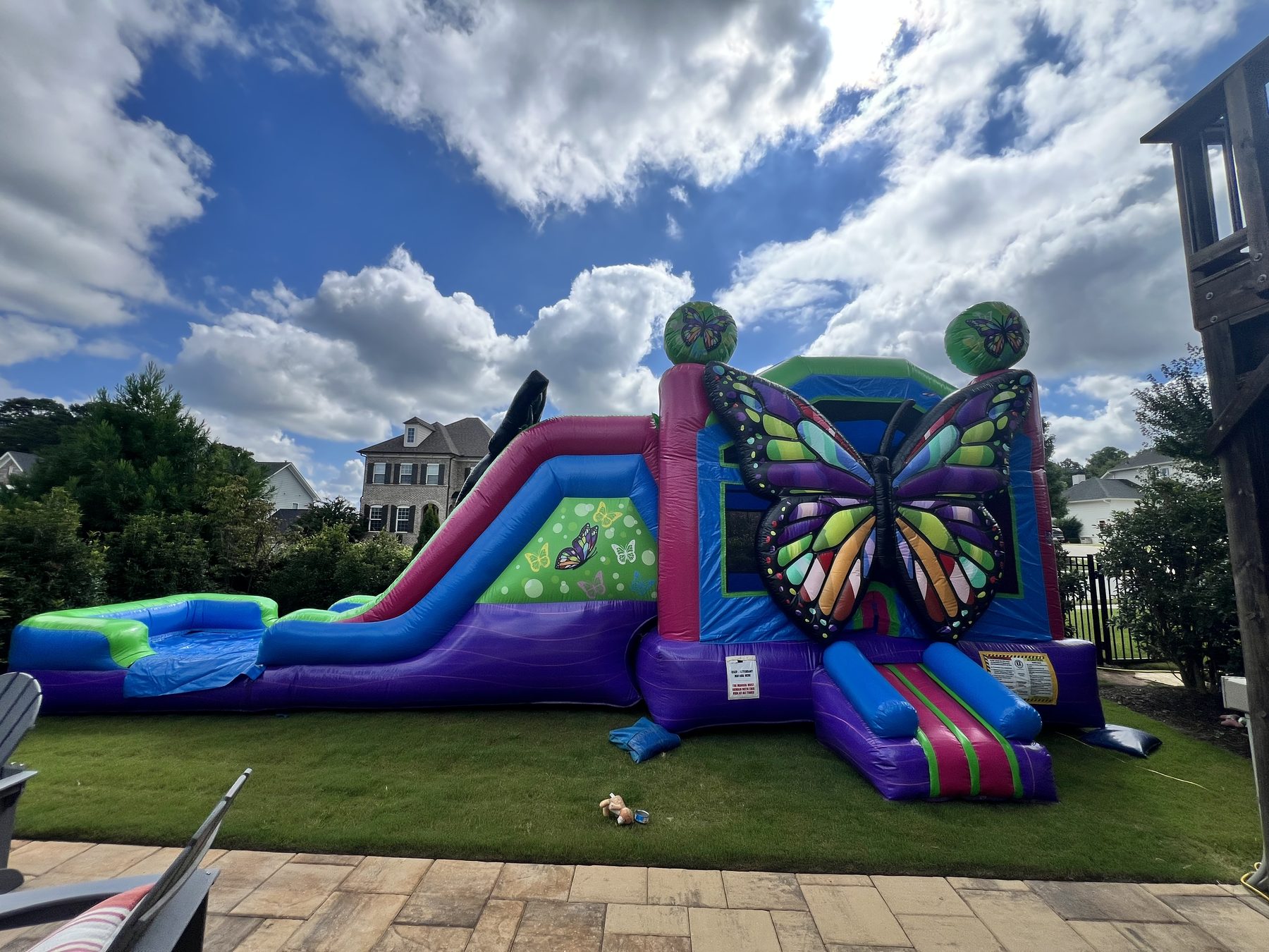 Butterfly bounce and slide combo professionally installed in a backyard