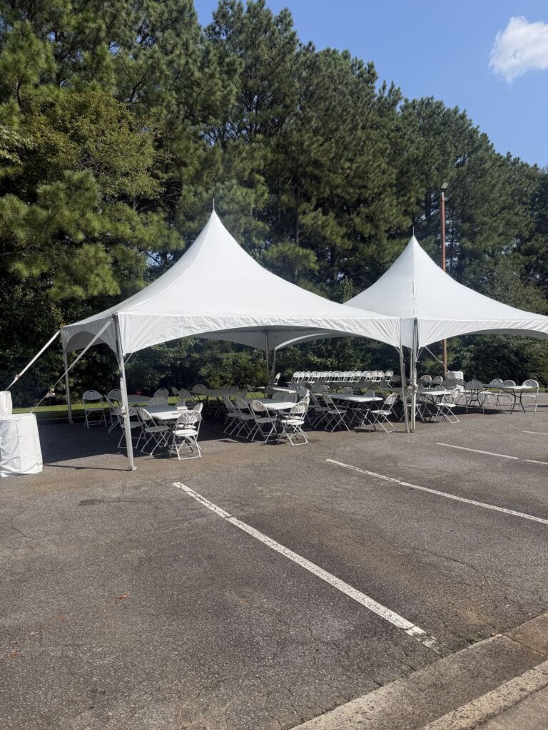 Connected white high-peak tents with seating and weights on pavement
